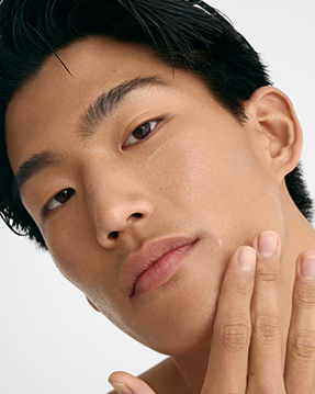 close up of a man with clear glowing skin, touching his face